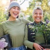 two women walking outside with plants